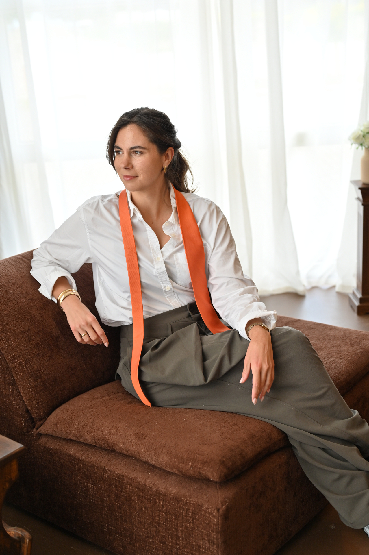 Jill zittend op de bank met een oranje das over haar schouders